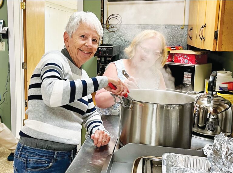 Volunteers Marion Berube (left) and JoAnne Jenkins work in the kitchen at St. Matthew’s Cathedral, Timmins, a parish that provides food service and outreach to neighbours in need. Photo: George Cribbs